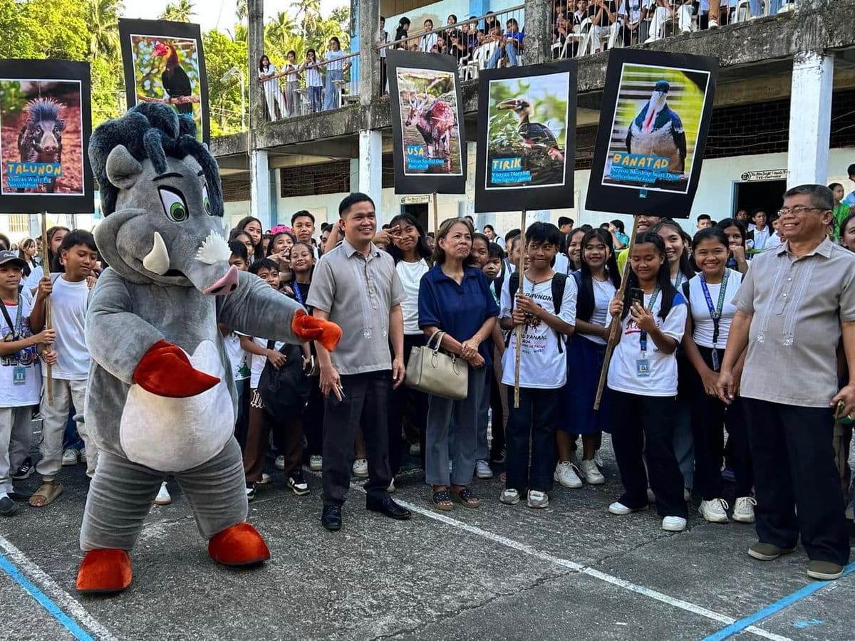A large mascot of a warty pig is standing in front of a group of people holding up placards of endangered animals in the Philippines