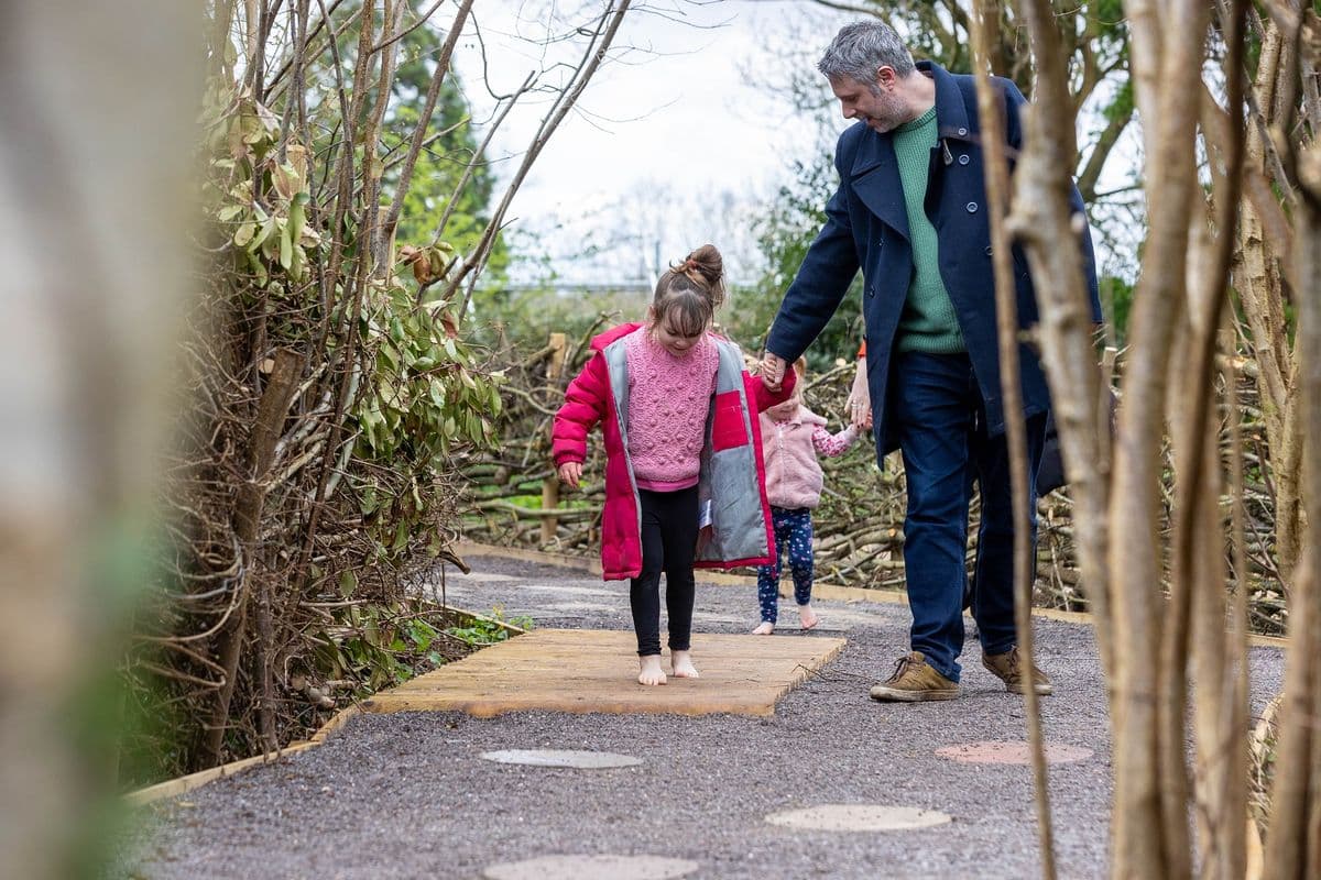 A child walking along a trail holding her father's hand